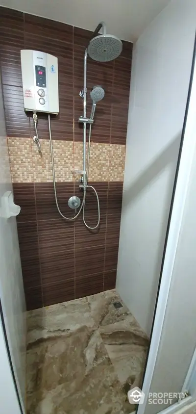 Modern bathroom with a sleek shower unit featuring both a rainfall and handheld showerhead, set against stylish brown tiles for a contemporary look.