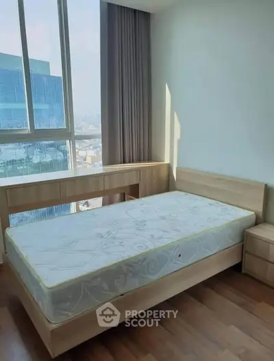 Modern bedroom with large window and wooden flooring, offering city views.