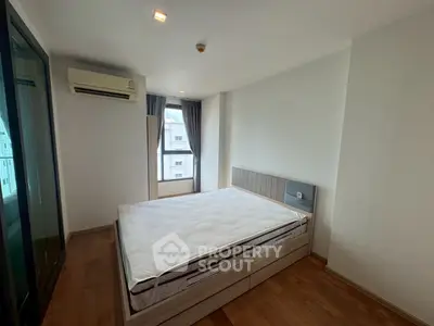 Spacious bedroom with large window and modern air conditioning unit in a stylish apartment.