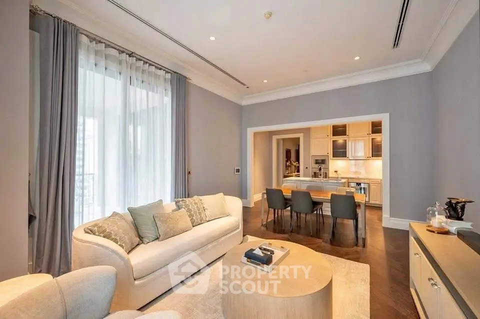 Luxurious open-layout living room with elegant furniture and modern kitchen in a high-end apartment.