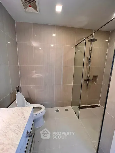 Modern bathroom with sleek glass shower and marble countertop in luxury apartment.