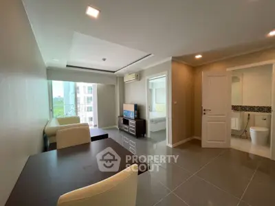 Modern apartment interior with open living and dining area, featuring sleek furniture and natural light.