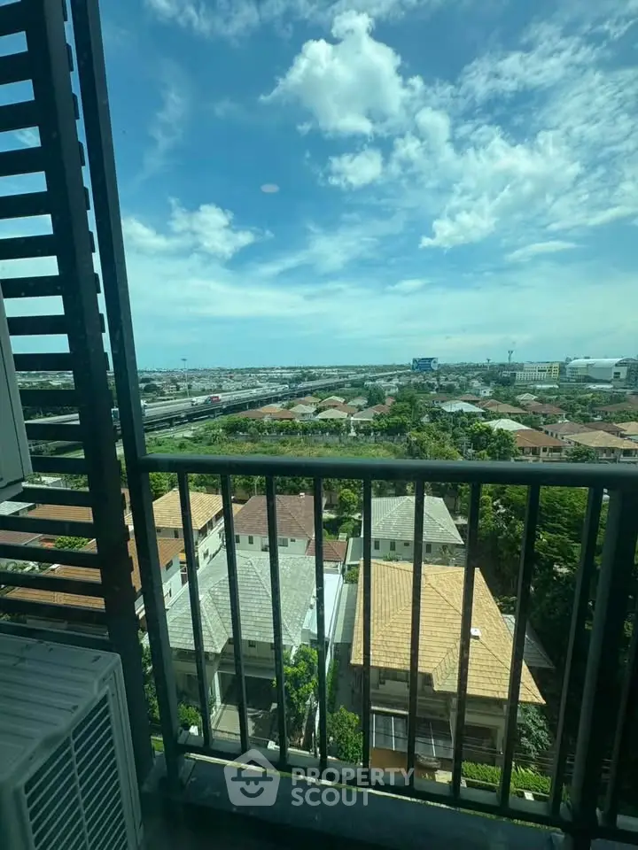 Stunning high-rise balcony view overlooking cityscape and lush greenery under a clear blue sky.