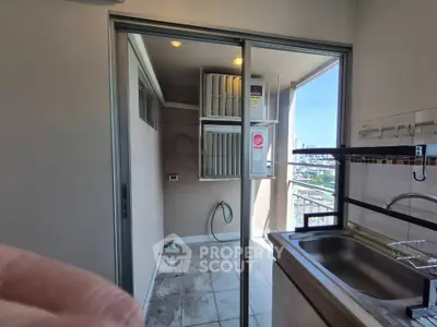 Modern balcony with utility area and city view, featuring sliding glass doors and compact sink setup.