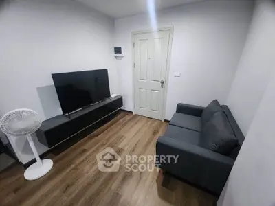 Modern living room with sleek TV setup and cozy gray sofa on wooden flooring.