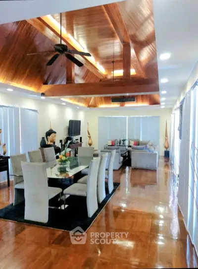 Luxurious open-plan living and dining area with high wooden ceilings and elegant decor.