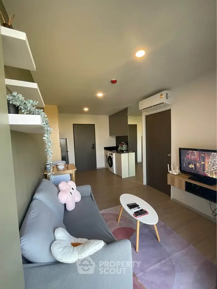 Modern living room with cozy sofa, TV, and open kitchen layout in stylish apartment.