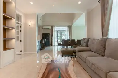 Spacious living room with elegant decor and natural light, featuring a stylish sofa and unique wooden table.