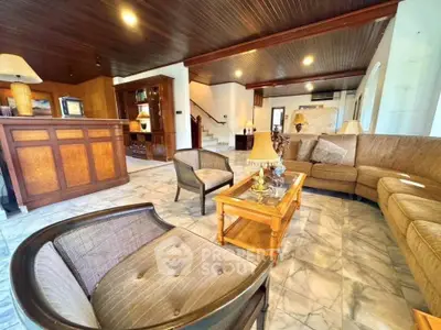 Spacious living room with elegant wooden ceiling and marble flooring, featuring cozy seating and stylish decor.