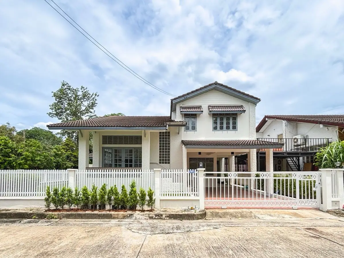 Charming two-story house with white picket fence and lush greenery, perfect family home in a serene neighborhood.