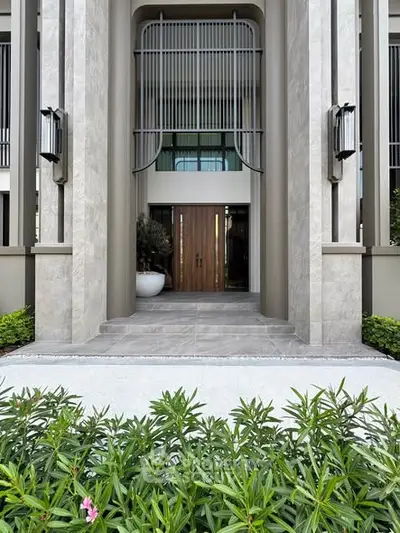 Elegant building entrance with modern architectural design and lush greenery