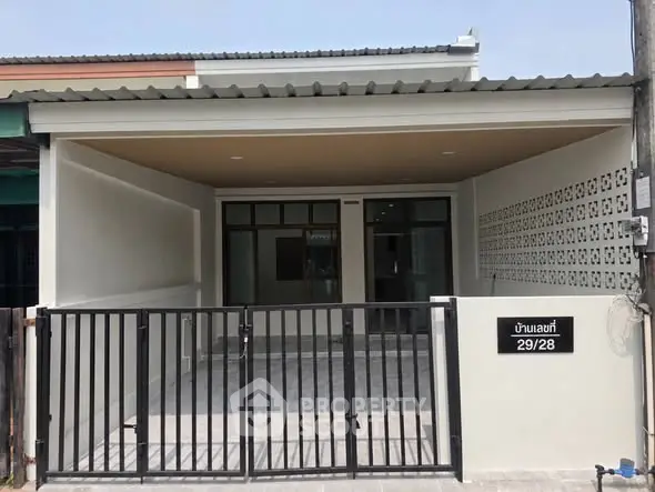 Modern single-story house with gated entrance and covered parking area.