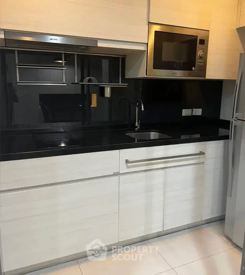 Modern kitchen with sleek black countertops and built-in appliances in a stylish apartment.
