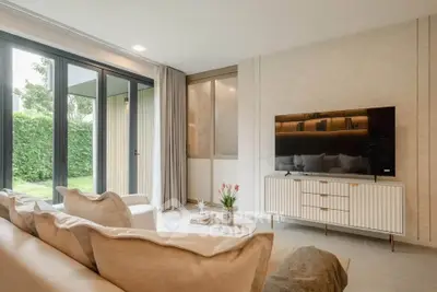 Elegant living room with modern decor and large windows overlooking lush greenery.
