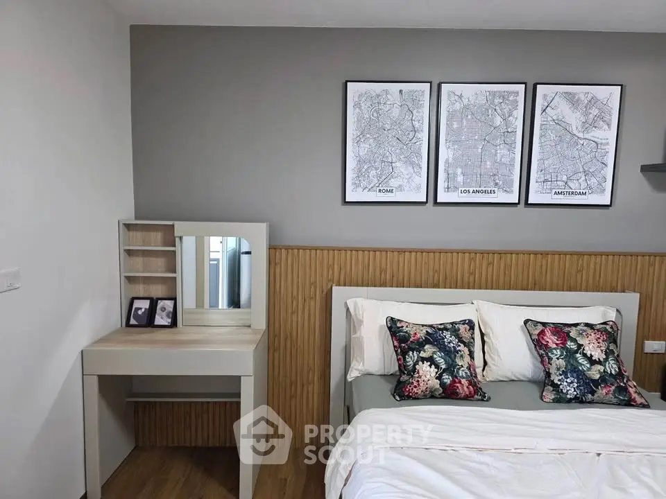 Chic bedroom with stylish decor and cozy bedding, featuring a modern vanity and framed city maps.