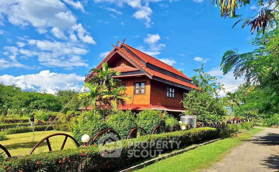 Charming traditional wooden house with lush garden and scenic surroundings under a vibrant blue sky.