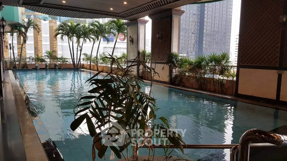 Luxurious indoor pool with city views and lush greenery in a high-rise building.