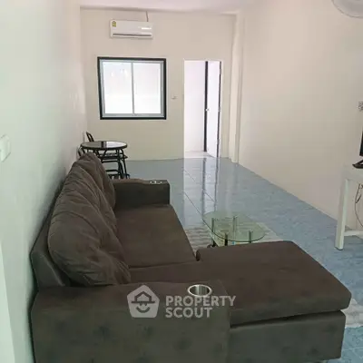 Spacious living room with modern sofa and natural light, perfect for relaxation and entertainment.