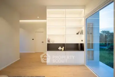 Modern minimalist living room with built-in shelving and large window view.