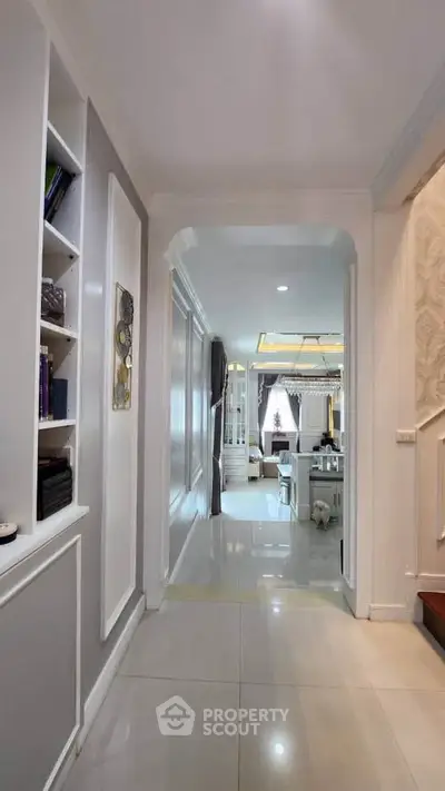 Elegant hallway leading to a luxurious living room with modern decor and ambient lighting.