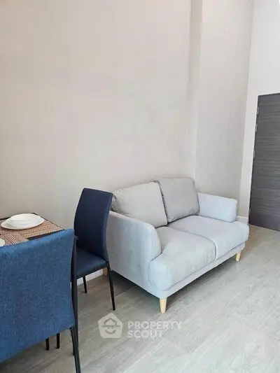 Modern living room with cozy gray sofa and dining area in stylish apartment.