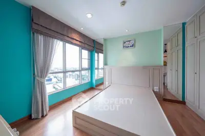 Spacious bedroom with large windows and built-in wardrobe offering city views.