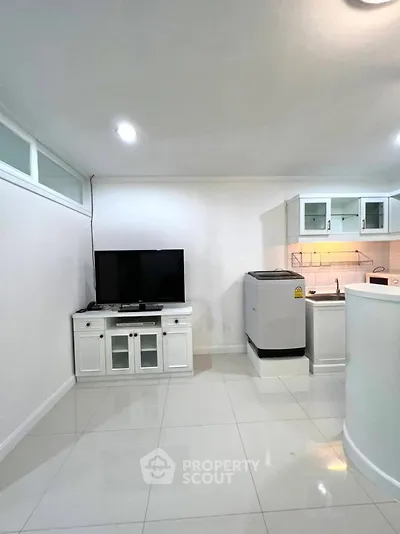 Modern living room with sleek white furniture and compact kitchen area