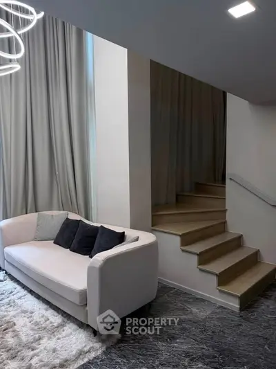 Modern living room with elegant staircase and cozy sofa, perfect for stylish urban living.