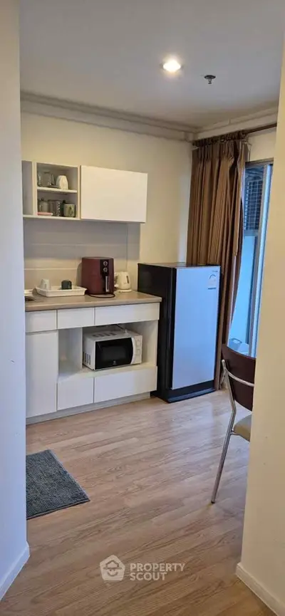 Cozy kitchen with modern appliances and wooden flooring in a compact apartment setting.
