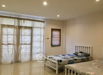 Spacious bedroom with twin beds and large windows for natural light.