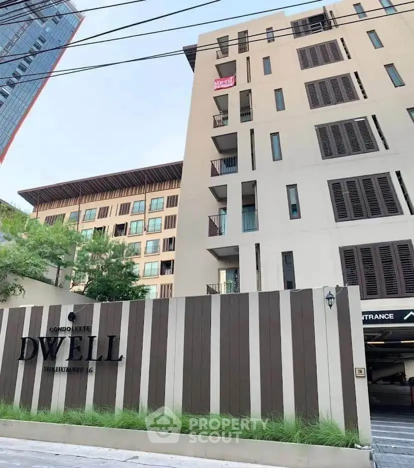 Modern condo building exterior with stylish facade and lush greenery.