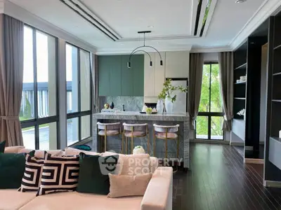 Luxurious open-layout living room with modern kitchen island and large windows offering natural light.