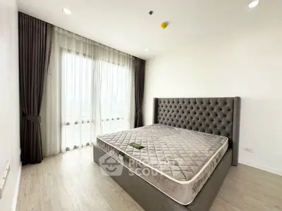 Spacious bedroom with large window and elegant bed frame in modern apartment.