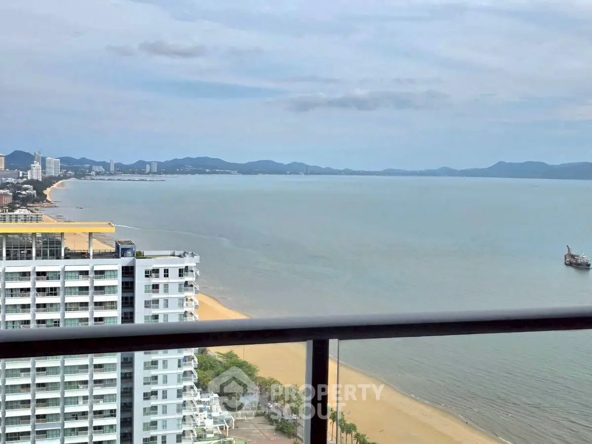 Stunning beachfront view from high-rise balcony overlooking serene ocean and city skyline.