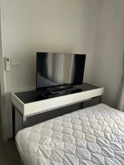 Modern bedroom with sleek TV setup and cozy bedding in a stylish apartment.