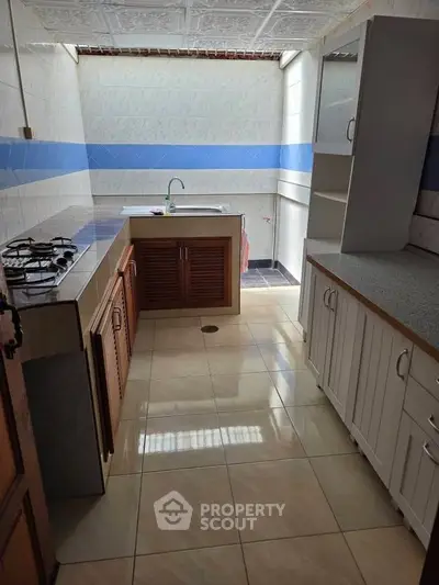 Spacious kitchen with tiled floors and ample cabinetry, featuring a gas stove and modern sink.