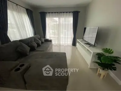 Spacious living room with modern sofa and large TV, perfect for relaxation.