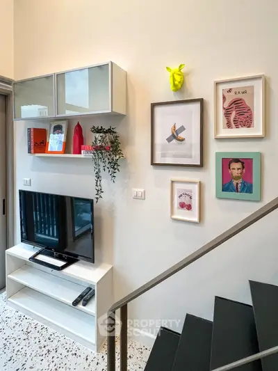 Stylish living room with modern decor and wall art, featuring a TV and staircase.