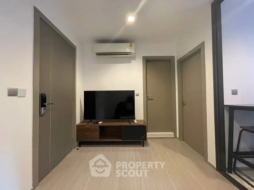 Modern living room with sleek TV setup and air conditioning in a stylish apartment.