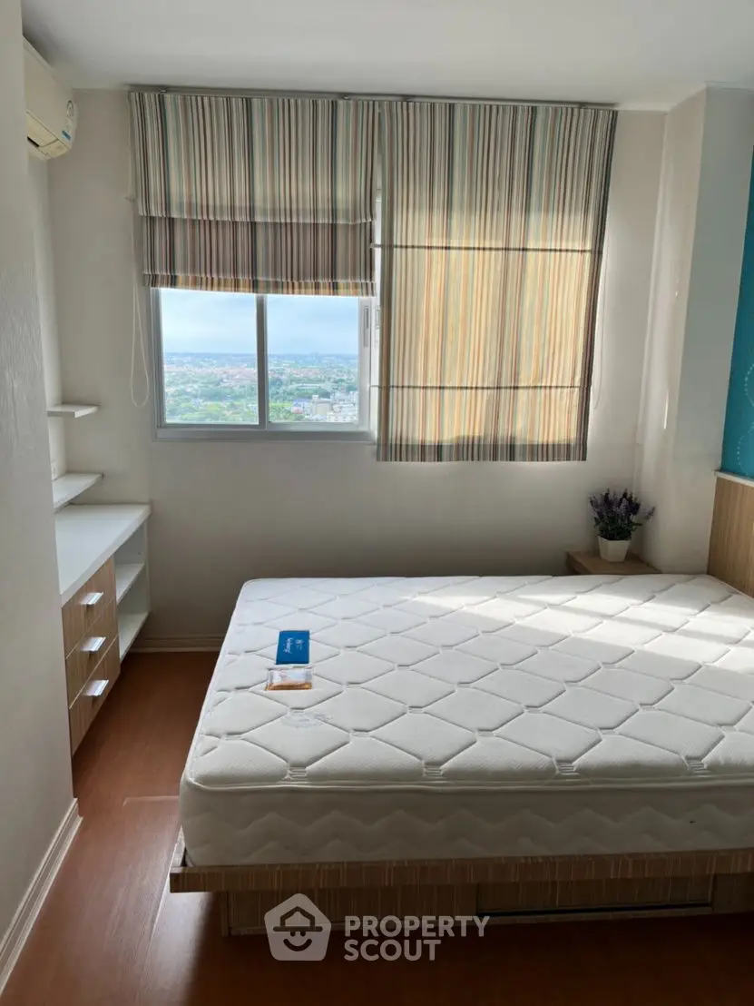 Bright bedroom with large window and striped blinds, offering a serene view and cozy atmosphere.