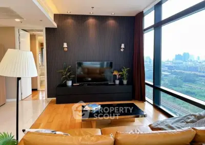 Modern living room with large windows offering stunning city views, featuring stylish decor and comfortable seating.