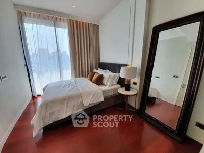 Luxurious bedroom with city view, elegant decor, and full-length mirror.