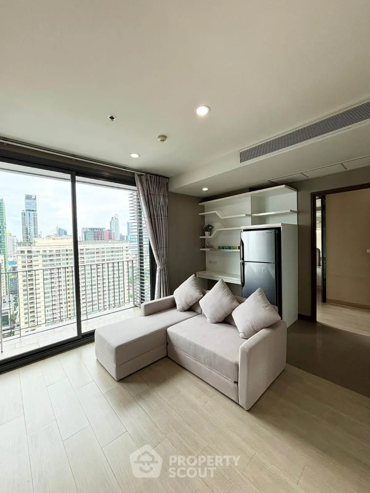 Modern living room with city view, featuring sleek furniture and large windows in a high-rise apartment.