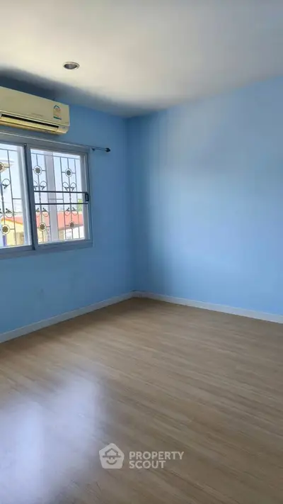Spacious empty room with wooden flooring and large window, perfect for customization.