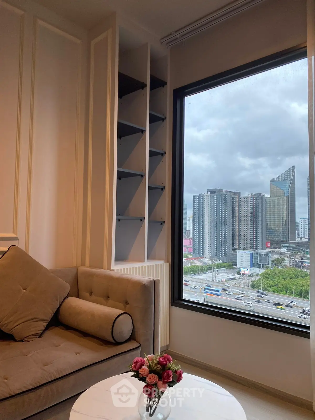 Chic urban living room with cityscape view from large window, featuring modern sofa and elegant decor.