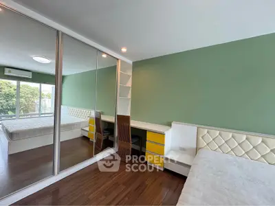 Spacious bedroom with mirrored closet and green accent wall in modern apartment