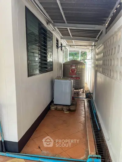 Outdoor utility area with water tank and washing machine in a residential property