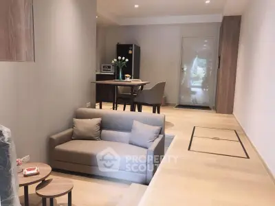 Modern open-plan living area with cozy sofa and dining space, featuring light wood flooring.