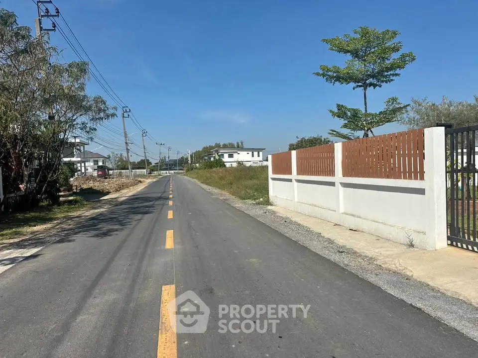 Scenic suburban road with modern houses and clear blue sky, ideal for peaceful living.