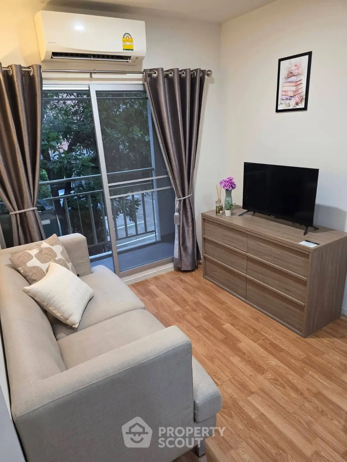 Cozy living room with modern decor, featuring a comfortable sofa, flat-screen TV, and sliding glass doors to a balcony.
